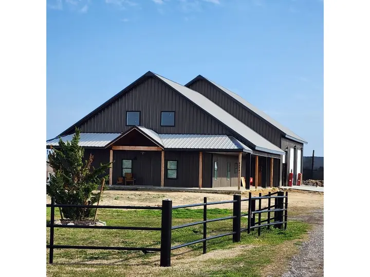 Brown barndominium with a stone and cedar porch