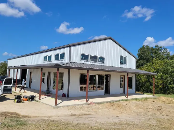 White barndominium with a wraparound porch